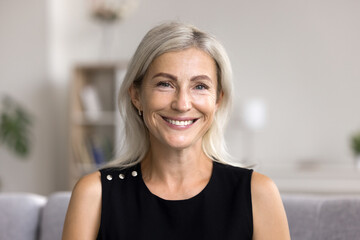 head shot portrait pretty blonde woman looking at camera, sits alone on sofa photoshooting, enjoy pl