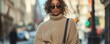 © Woranittha - A woman in an oversized sweater and wide-leg pants, accessorized with a crossbody bag and statement sunglasses, highlighting the relaxed, chic aesthetic of street fashion