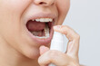 © Марина Демешко - Close up of a young caucasian woman using spray to freshen a breath on a light background. Vitamins in the spray
