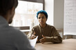 © fizkes - Young blue-haired African woman passes job interview, sit table in front of male HR manager answer questions, looks serious and confident. Business meeting, negotiations, human resources and hiring