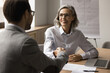 © fizkes - Smiling middle-aged 50s businesslady and happy businessman shaking hands, establish partnership, expressing respect. Gesture of trust and mutual understanding between business partners or colleagues