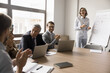 © fizkes - Laughing businesspeople gathered in boardroom, take part in educational seminar, meeting briefing event led my happy mature businesslady, company boss or team leader making flip chart presentation