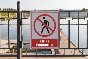 Enter Forbidden - a simple white and red warning sign on a black metal fence, with a lake in the background