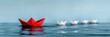 © Inlovehem - Red paper boat leading white paper boats on calm water, symbolizing leadership, teamwork, and creativity in a minimalist setting.