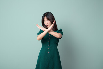 Young woman expressing disapproval with crossed arms, wearing green dress.