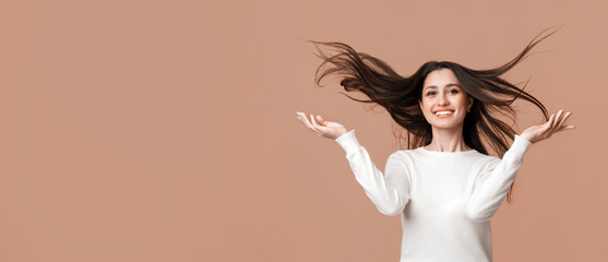 Hair Care. Portrait of beautiful brunette woman with long shiny flying hair posing over yellow background