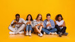 © Prostock-studio - Multiracial teenagers sitting on floor and texting with their smartphones, yellow background, concept about technology and global communication