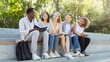 © Prostock-studio - friendly multiethnic group of students discussing new educational project, sitting with notepads on stairs in park