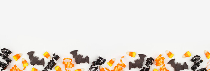 Poster - Halloween bottom border of black, white and orange color candy and ribbon. Top view on a white banner background with copy space.