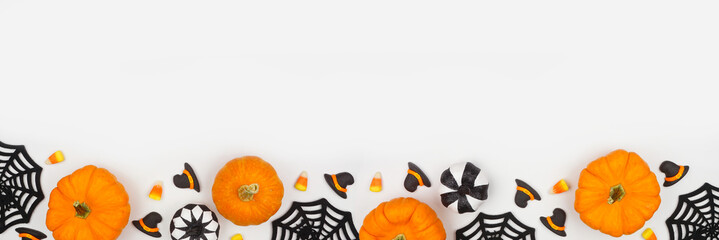 Aufkleber - Halloween bottom border of black, white and orange color candy, pumpkins and decor. Top down view on a white banner background with copy space.