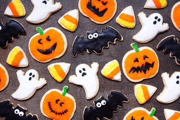 Poster - Halloween cookie background. Top down view on a dark stone background. Ghosts, bats, jack o lanterns and candy corn.