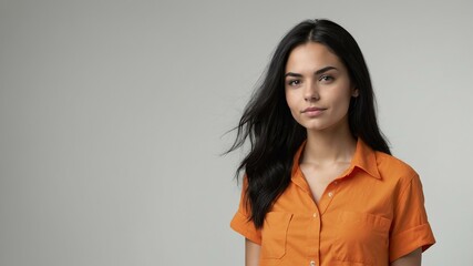 Wall Mural - teen stunning black hair white woman with orange shirt model portrait standing straight on a plain w