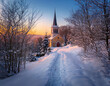 © MediaPro - Chemin enneigé qui mène à l'église du village au coucher de soleil
