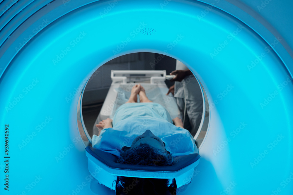 Individual undergoing MRI scan within medical facility while technician ...
