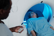 © Clique Images - Person lying inside MRI scanner receiving diagnostic imaging with medical personnel operating machine nearby