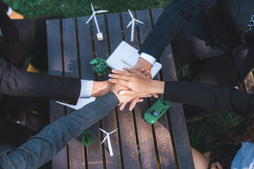 Wall Mural - Business people join hand together as teamwork and unity, outdoor business meeting table. Eco-friendly practices and collaboration in corporate social responsibility for greener environment. Gyre