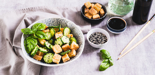 Wall Mural - Fresh cucumber and fried tofu salad with basil leaves in bowl on table web banner