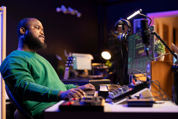Leinwandbilder - Sound engineer playing piano and mixing tunes on digital software, composing new songs and adding audio effects in post production. Artist composer creating soundtracks for music industry.