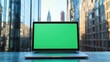 © Aliaksandr Siamko - A laptop with a green screen sits on a table in front of a city skyline