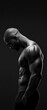 © PTC_KICKCAT - Dramatic black and white photograph of a muscular man with a bald head, showcasing his strong physique and defined muscles in low light.