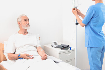 Wall Mural - Senior man with emergency call button and nurse setting IV drip in hospital, closeup