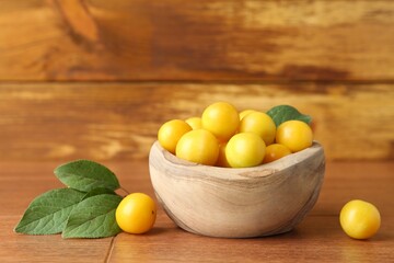 Wall Mural - Ripe plums in bowl and leaves on wooden table