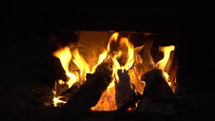 Wall Mural - Fire burns wood in the fireplace. Dark shades around it