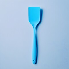 Poster - Bright Blue Spatula Centrally Placed on a Plain and Minimalist Surface Showcasing the Elegance and Simplicity of the Kitchen Utensil in a Stylish Abstract Composition