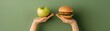 © Chanoknan - A healthy apple and a delicious burger balanced in hands, symbolizing choices in food and lifestyle.