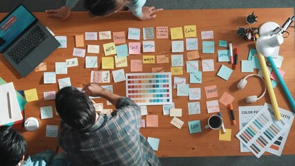 Poster - Top down view of business team with casual outfit looking laptop screen and sharing idea. Aerial view of manager working and checking color palette at table with sticky notes and headphone. Symposium.