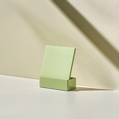 Poster - Closeup view of a green sticky note holder placed at the center of a light surface  Minimalist office supplies and stationery accessories for a tidy and organized workspace