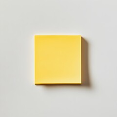Poster - High Angle Shot of a Vibrant Yellow Sticky Note Pad Placed at the Center of a Clean White Background