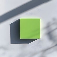 Poster - Close up of a green sticky note holder placed centrally on a plain white surface  The simple minimalist design of the office accessory is showcased in an overhead flat lay product display