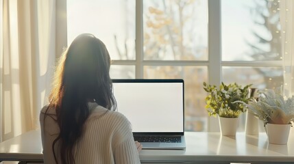 Poster - Focused young woman working on a laptop with a blank copy space screen, ideal for mock-up designs and digital workspace concepts, featuring a modern home office setting with a clean desk and minimalis