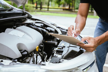 A technician in a Thailand auto repair shop conducts diagnostics on a car engine using a laptop. The scene highlights advanced technology in automotive inspection and repair.