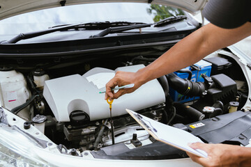 A technician in a Thailand auto repair shop conducts diagnostics on a car engine using a laptop. The scene highlights advanced technology in automotive inspection and repair.