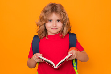Aufkleber - School boy with book and apple. School child student learning. Elementary school child. Portrait of funny pupil learning on yellow isolated background.
