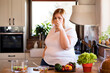 © Halfpoint - Overweight woman in the kitchen, drinking cup of fresh tap water. Choosing healthy diet, making vegetable salad.