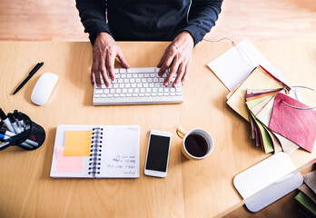 Wall Mural - Close up of man working from home office, coffe, smartphone and planner with notes on desk. Telecommuting and home office.