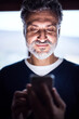 © Halfpoint - Portrait of handsome man looking at smartphone screen. Display glow illuminates man's face.