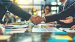 © Mr Muslich - Businesspeople shaking hands over a table of documents.