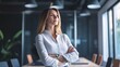 © Jiraphat - A confident woman stands with arms crossed in a modern office, showcasing determination and professionalism in a corporate setting.