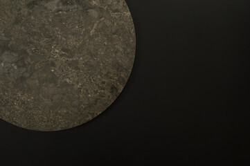 Top view of brown marble plate on black background. Food presentation, stone tray. Copy space, flat lay.