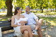 © KONSTANTIN SHISHKIN - Young family relaxing on a park bench in the summertime