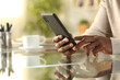 © PheelingsMedia - Black man hands checking cell phone at home on a desk