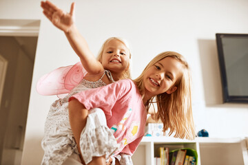 Fly, piggyback and portrait of girls in home or fairy costume for dress up, fantasy play or tiara with smile. Family siblings, happy kids or sisters playing with wings or princess outfit for bonding