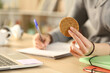 © PheelingsMedia - Student studying taking notes holding cookie