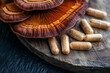 © StellaPattaya - reishi mushroom tablets capsules. trending superfood with health benefits, Traditional Chinese Medicine mushrooms on wooden podium, dietary supplement banner for sale