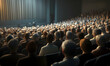 © Putu - Back view of an audience in a large conference hall, looking at the speaker on stage.