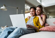 © Westend61 - Happy woman leaning on boyfriend using laptop on sofa at home